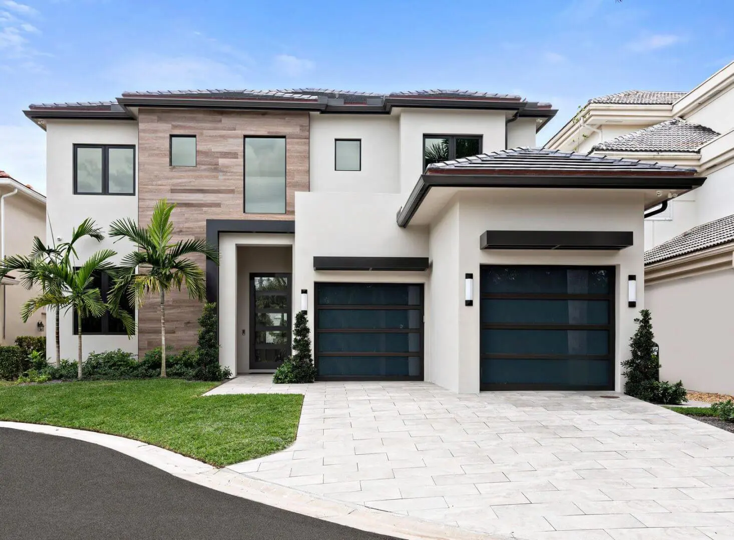 A large white house with two black garage doors.
