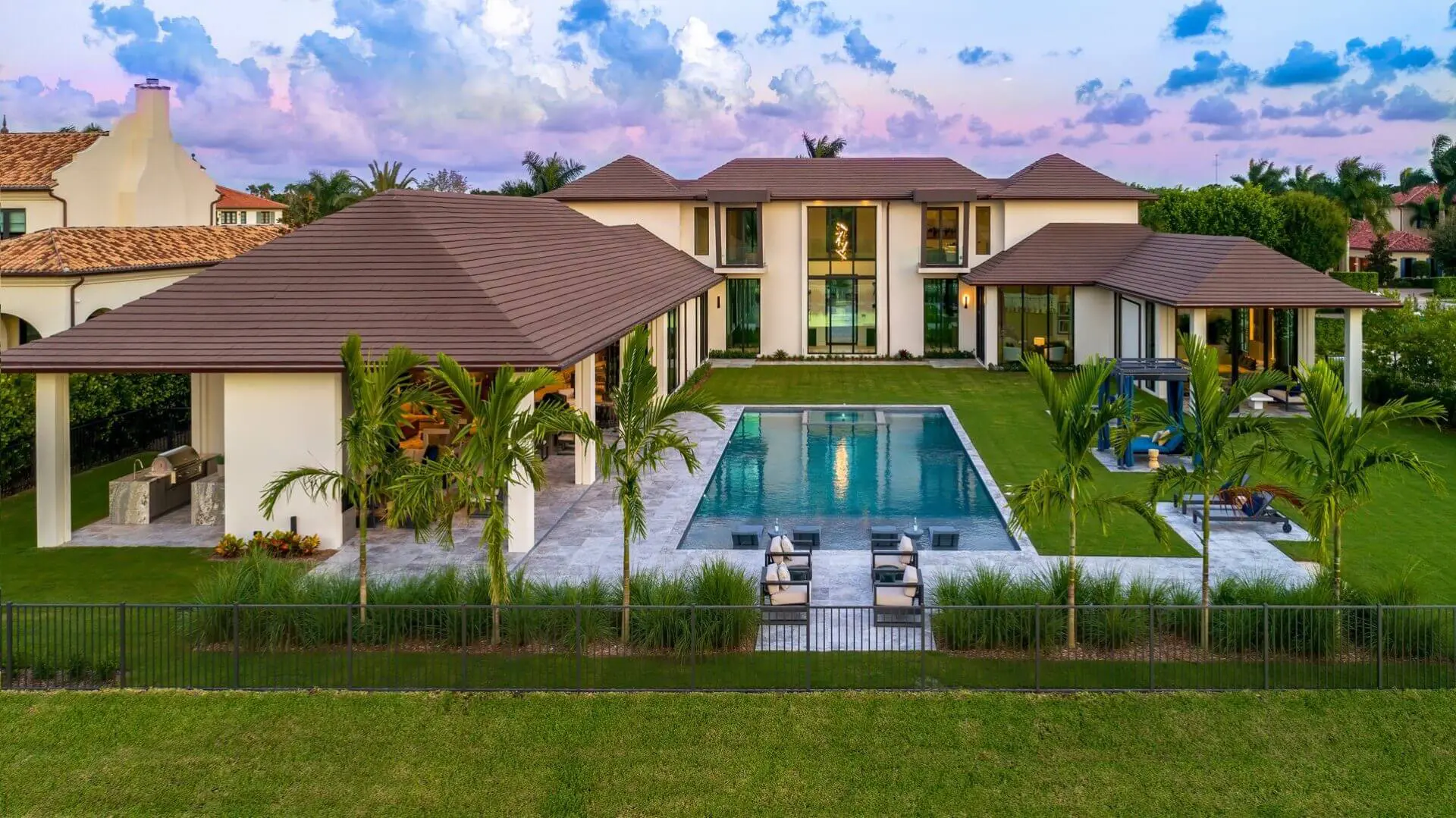 A large pool in front of a house with grass.