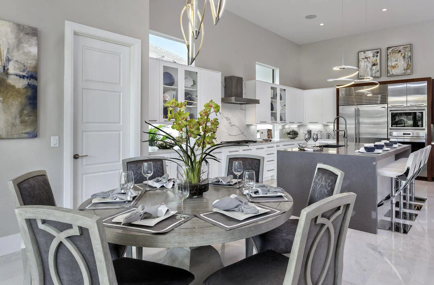 A dining room table with four chairs and a vase of flowers.