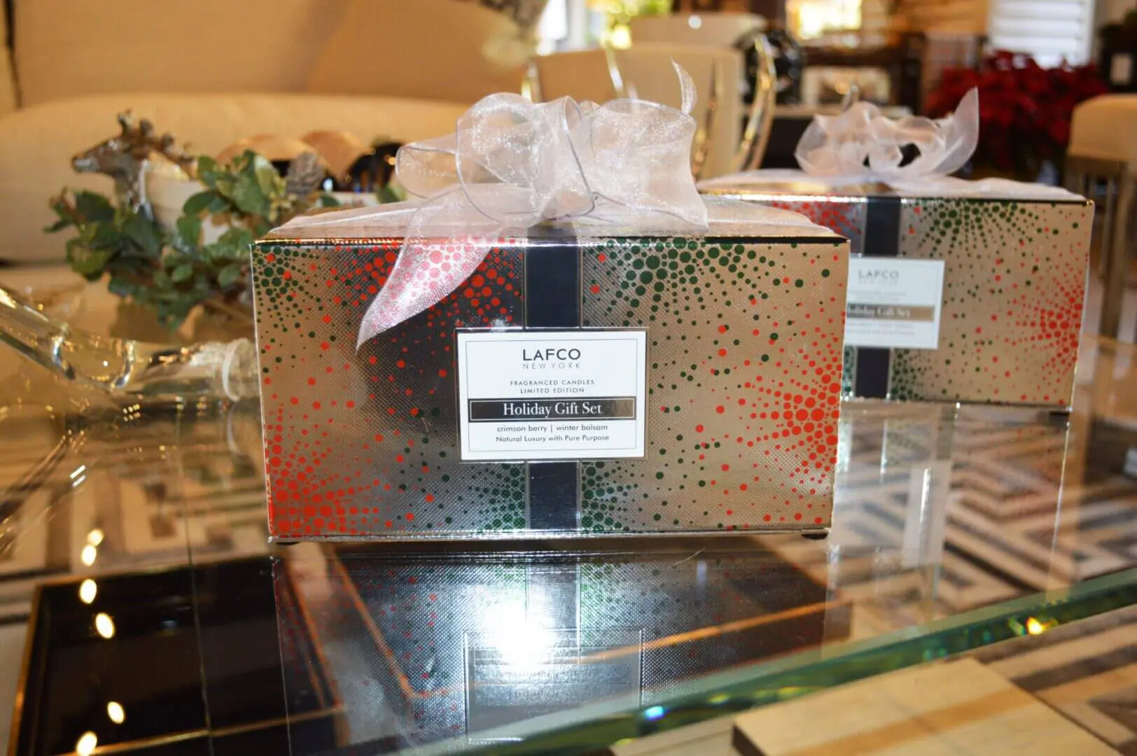A gift box with ribbon and bow on top of glass table.