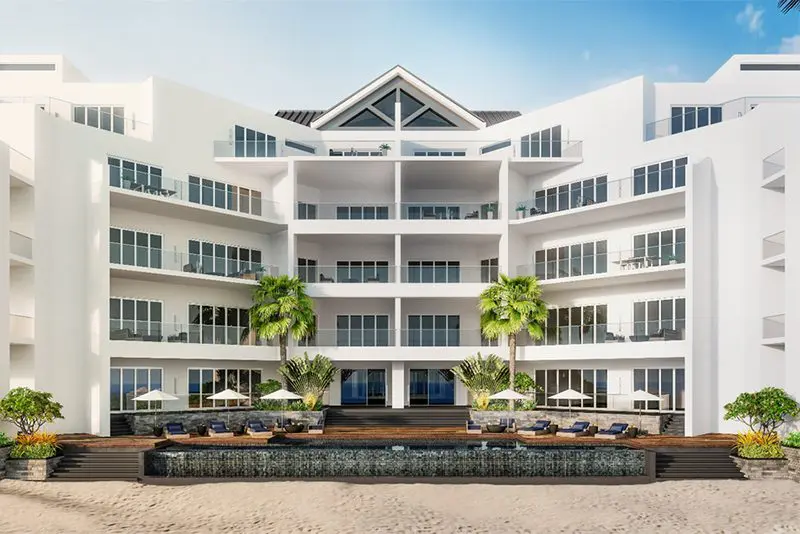 A large building with palm trees and blue chairs.