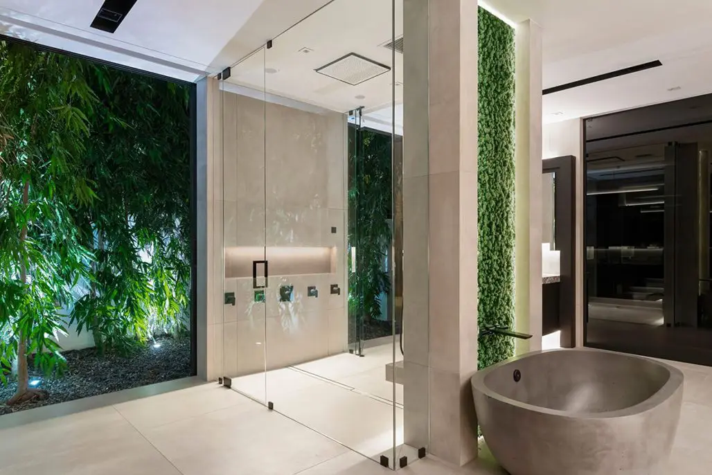Bathroom with a large tub and a walk-in shower, surrounded by glass walls and a lush green wall