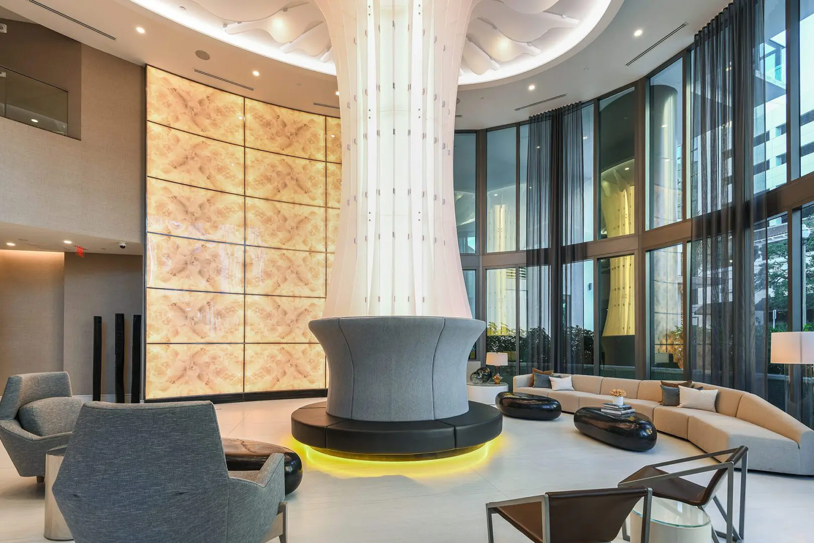 Large lobby with a curved reception area, featuring a sofa set with cushions, chairs, tables, side tables, table lamps