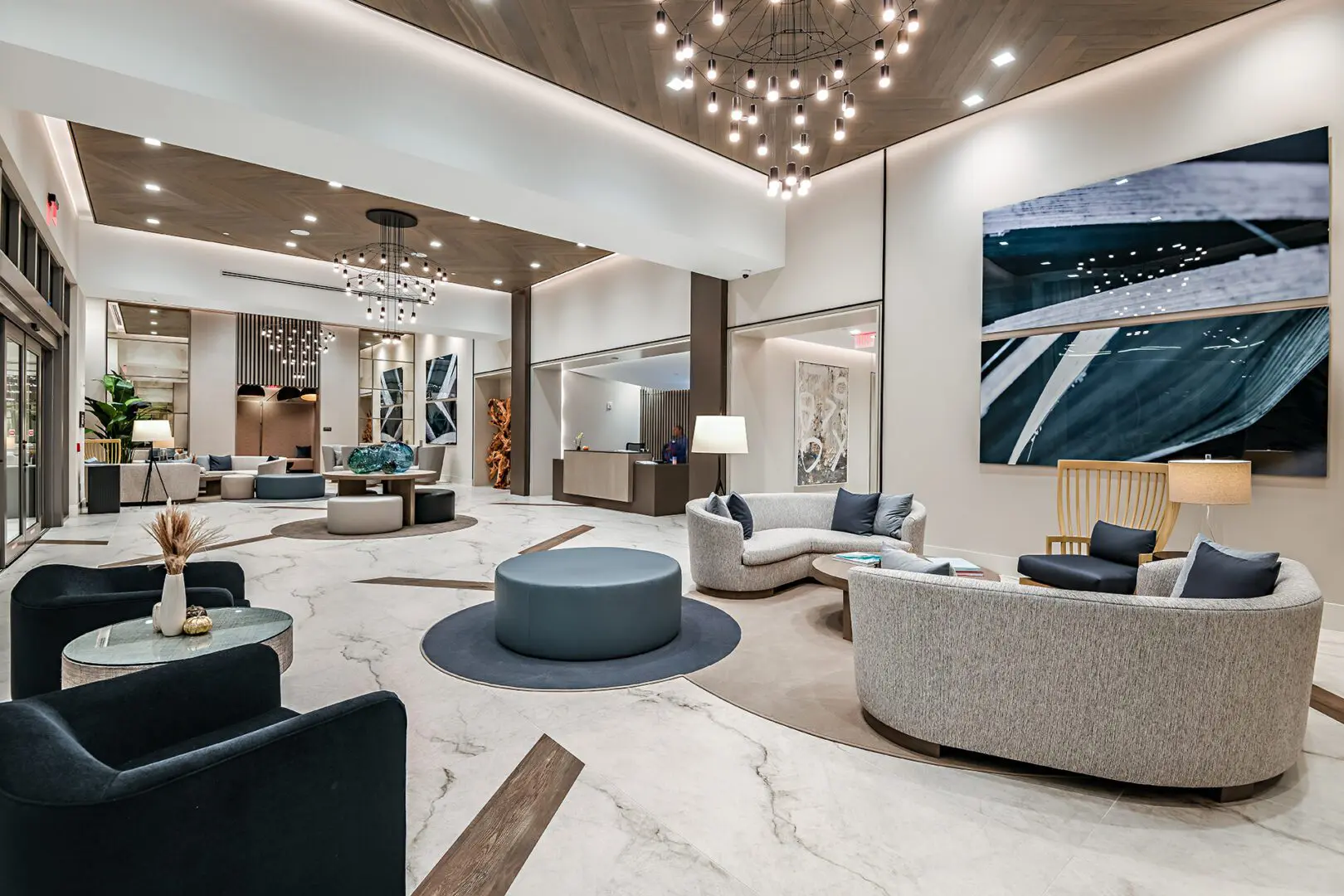 Large lobby with a variety of furniture, including sofas with pillows, tables with flower vases, chairs, lamps