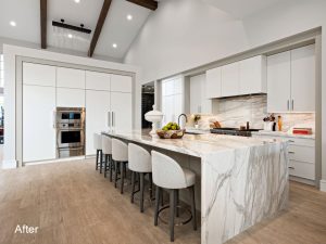 A large kitchen with white marble counter tops and island.