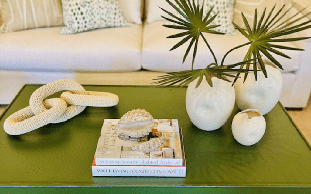 A green coffee table with books and vases on it