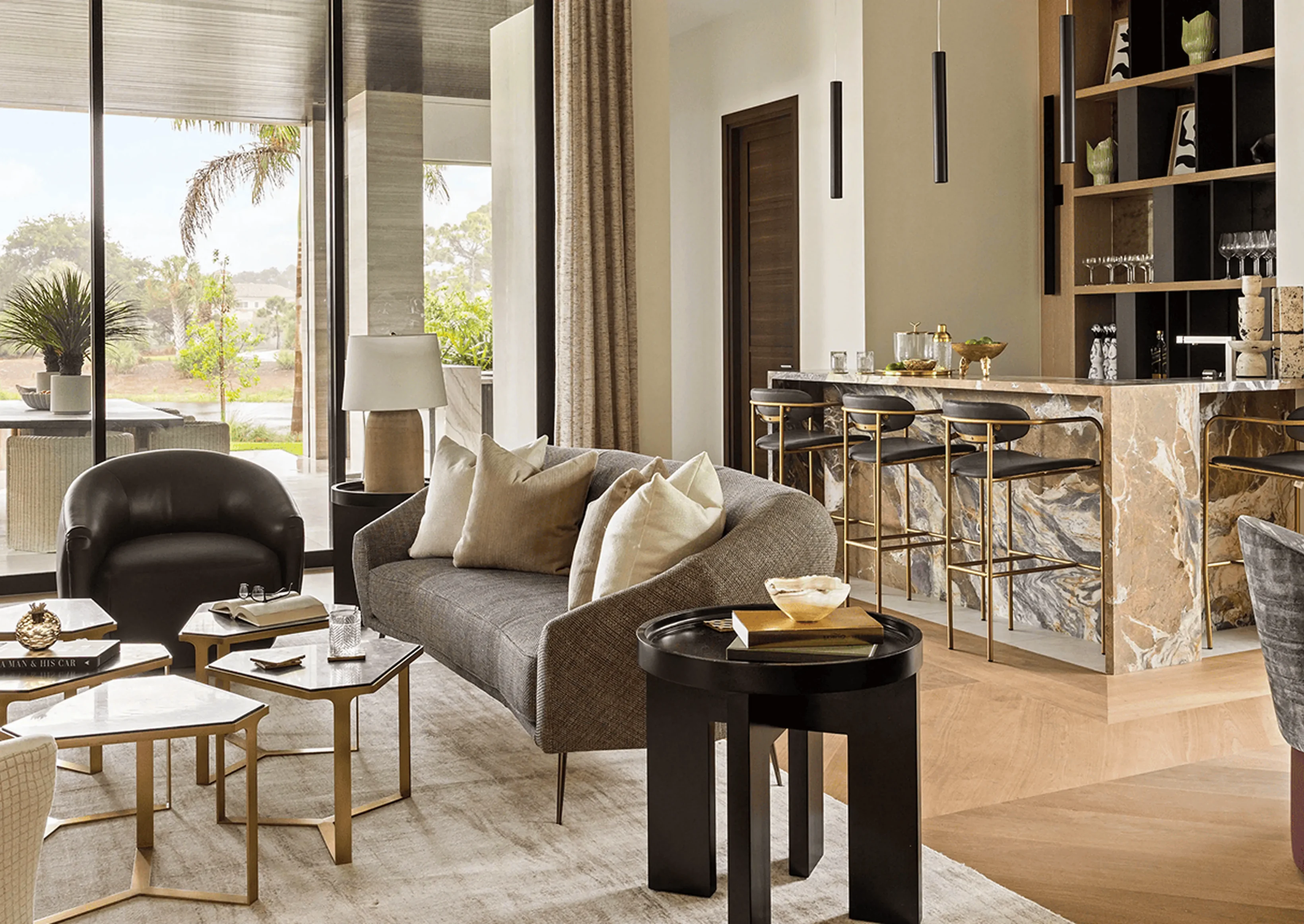 Living room filled with furniture such as a sofa with cushions, chairs, tables, books, glasses, a bowl, and other objects