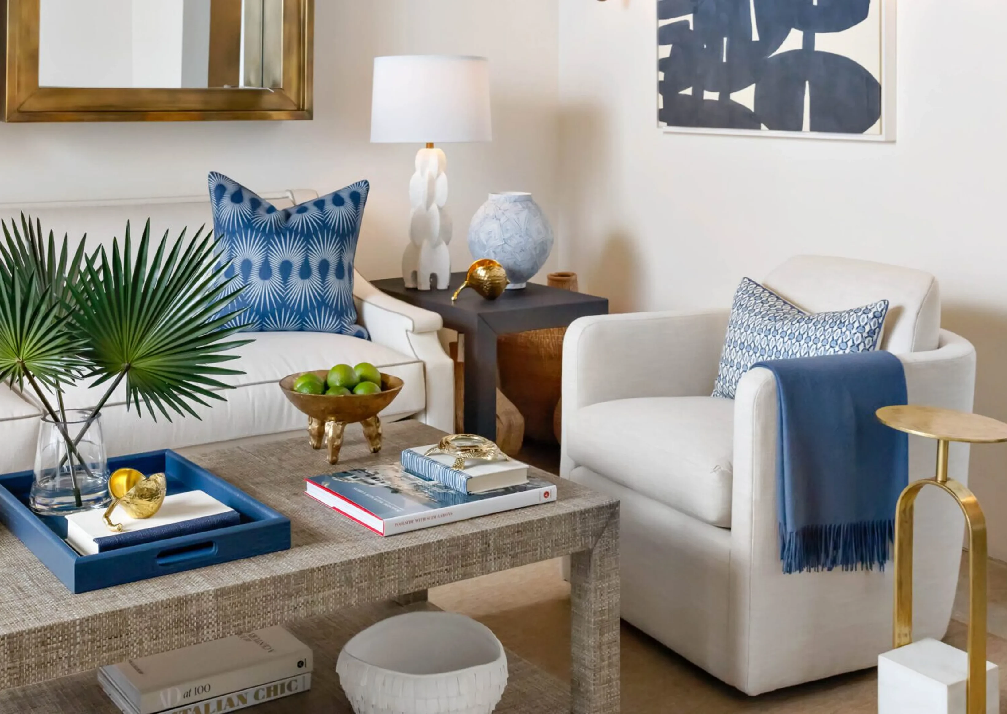 Living room with two white couches and a coffee table, adorned with blue and white accents