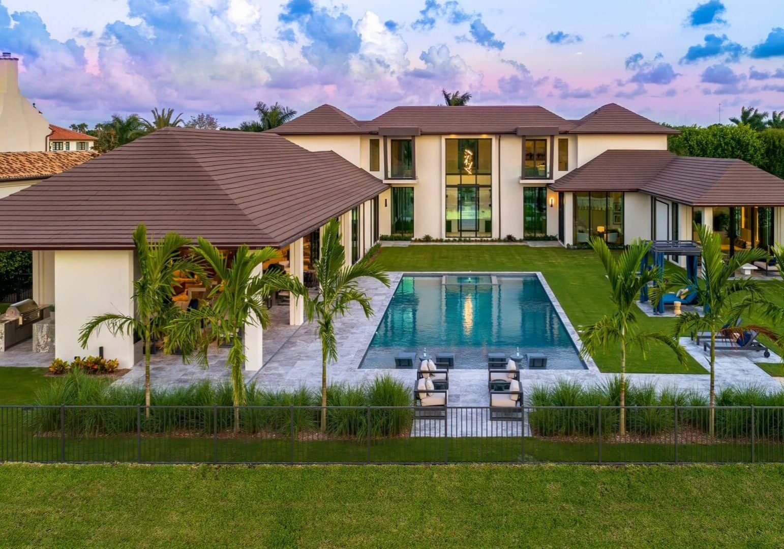 A large pool in front of a house with grass.