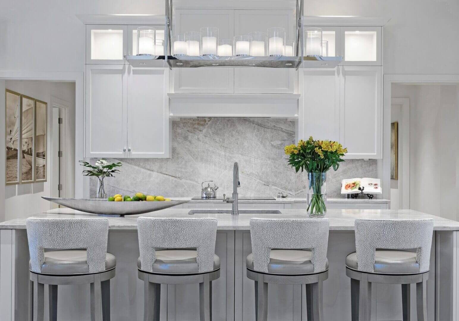 A kitchen with white cabinets and marble countertops.