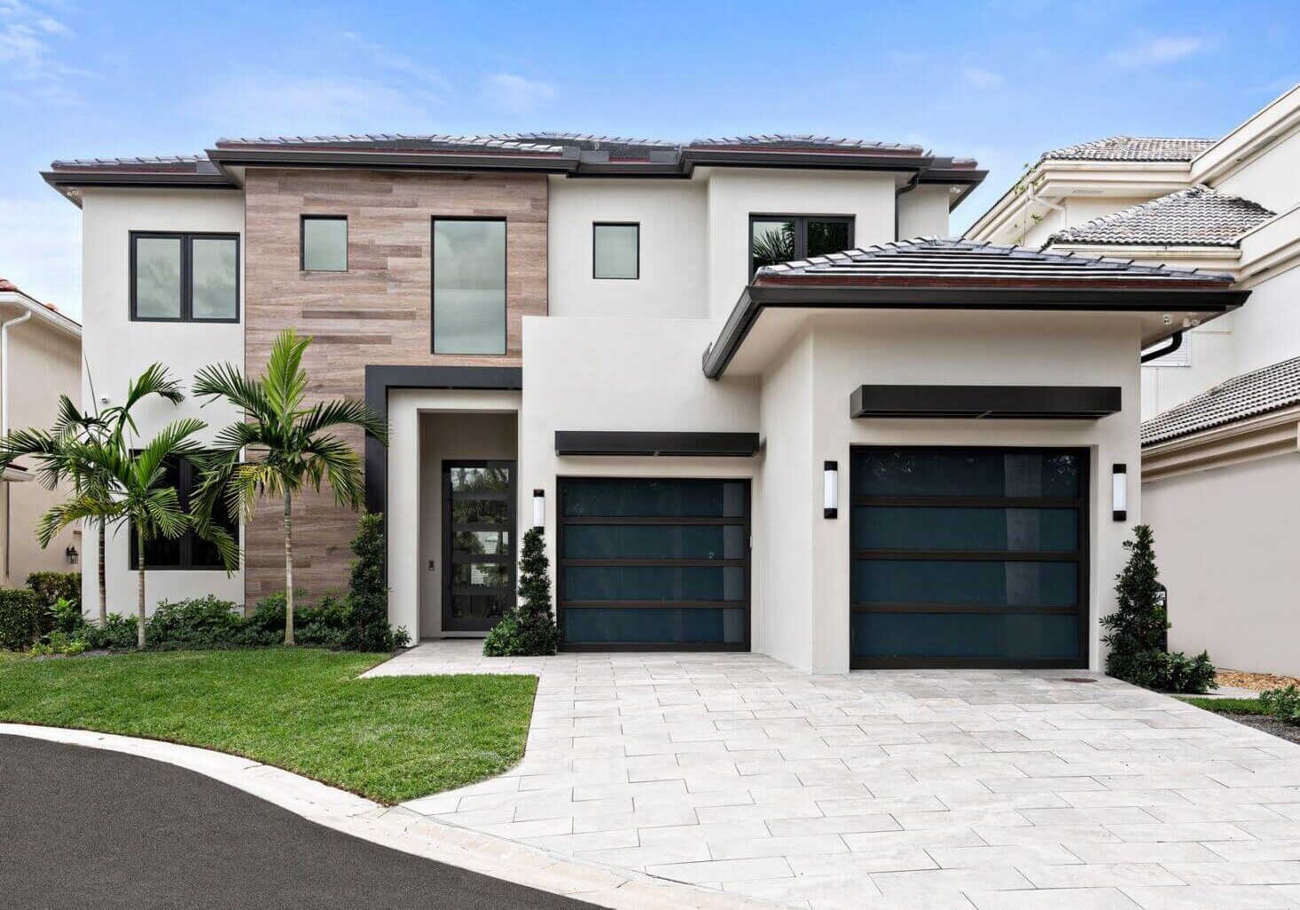 A large white house with two black garage doors.