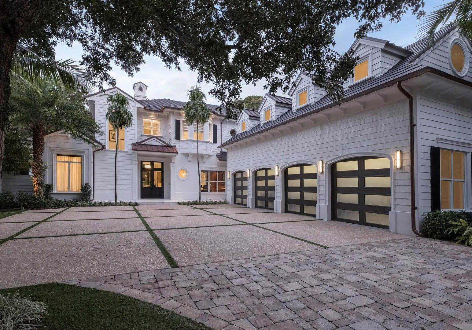A large driveway with two garage doors and a tree.