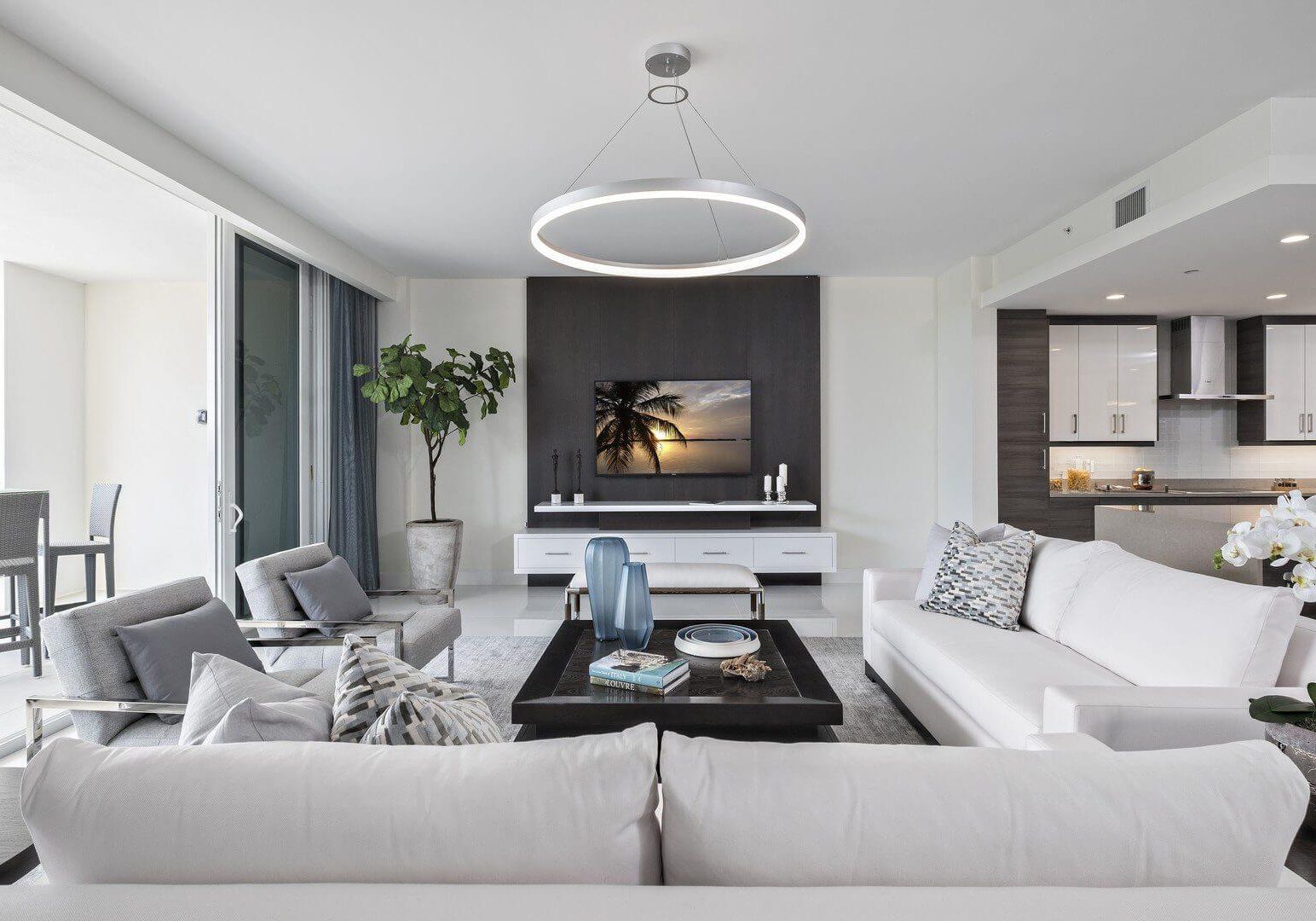 A living room with white furniture and a flat screen tv.