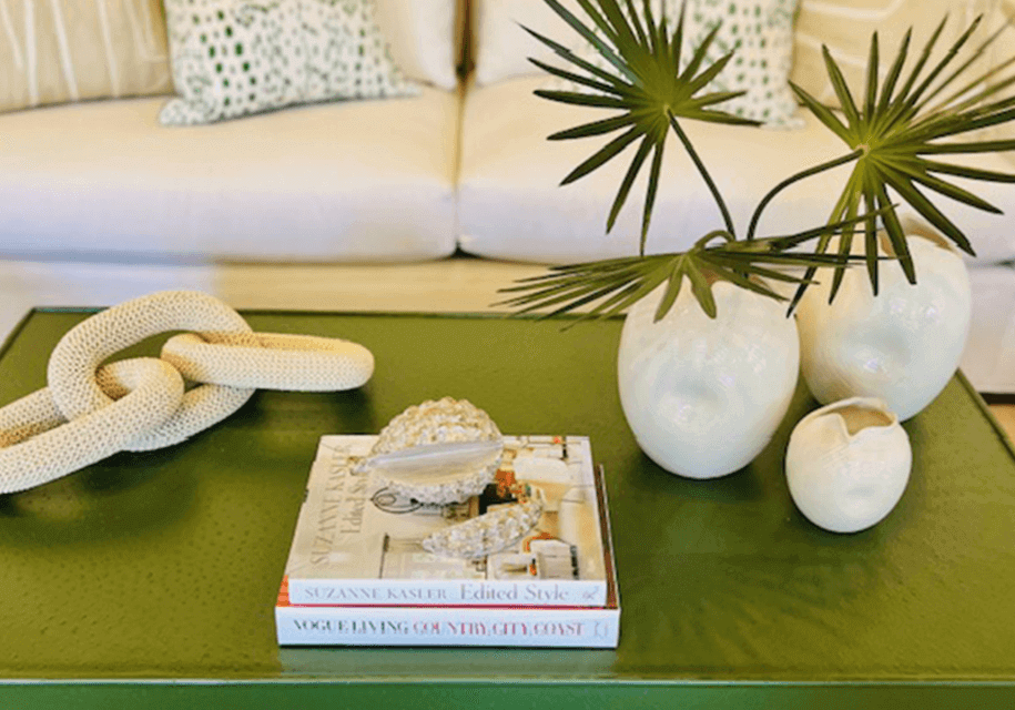 A green coffee table with books and vases on it