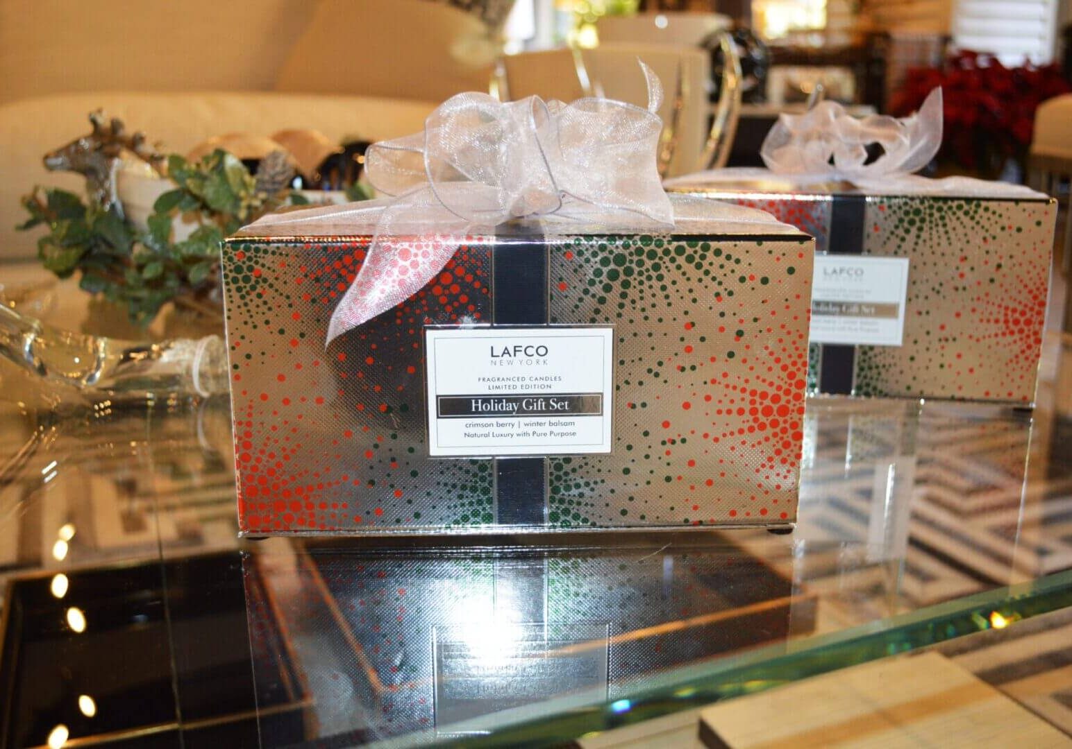 A gift box with ribbon and bow on top of glass table.