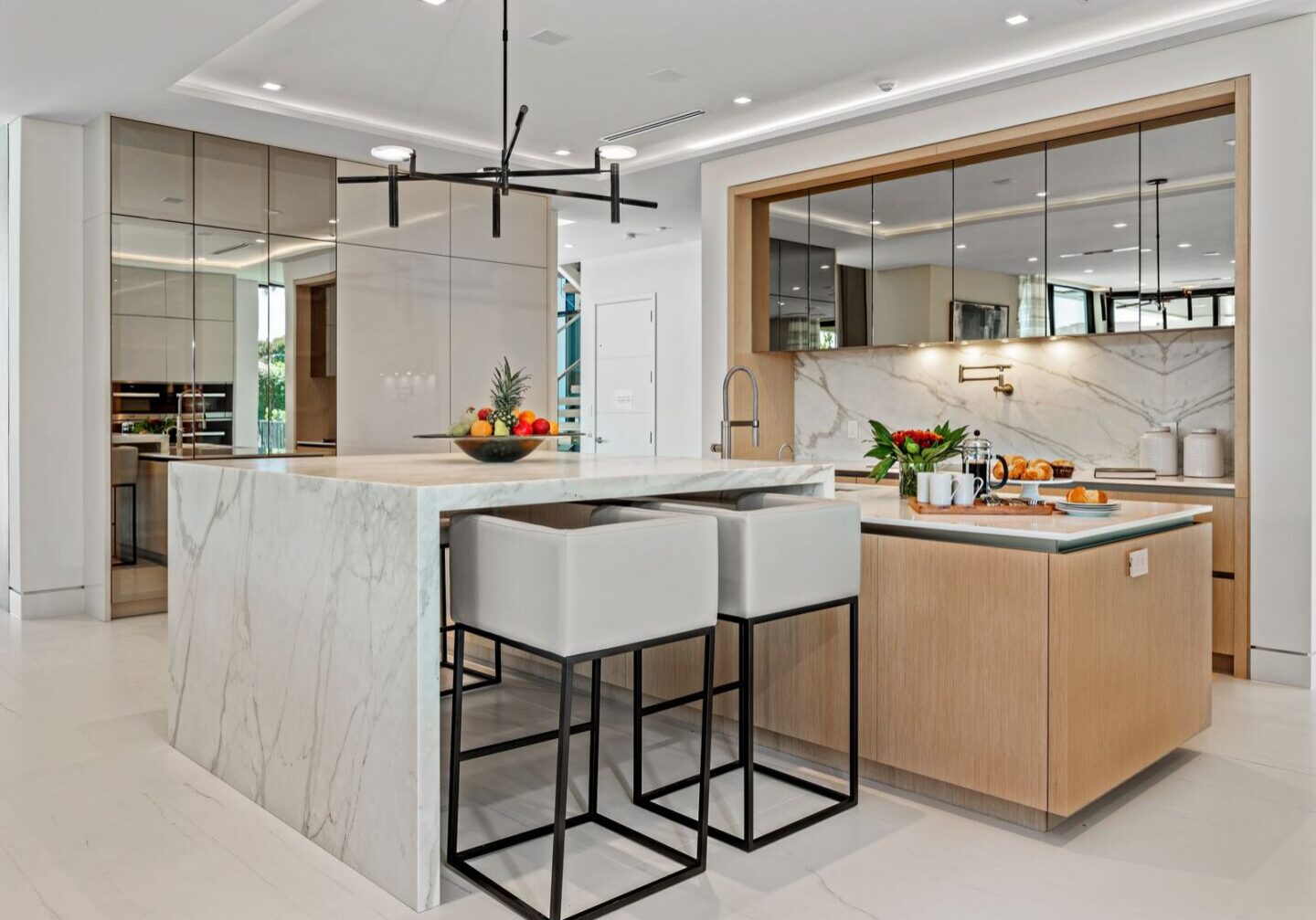 A kitchen with marble counter tops and white cabinets.