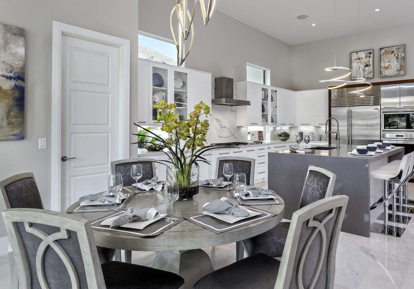 A dining room table with four chairs and a vase of flowers.