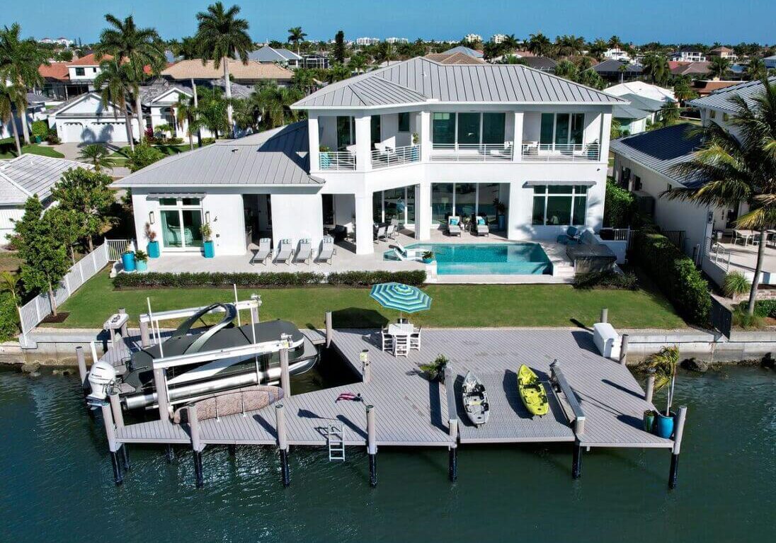 A large white house with a dock in the middle of it.