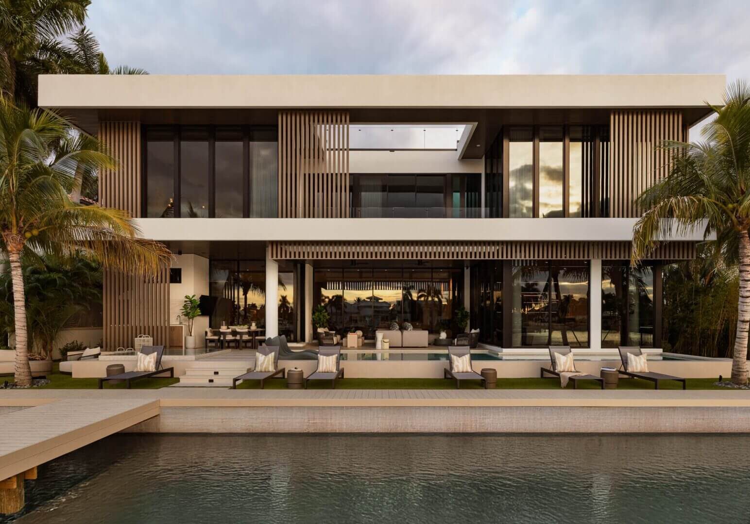 Modern waterfront house with large glass windows.