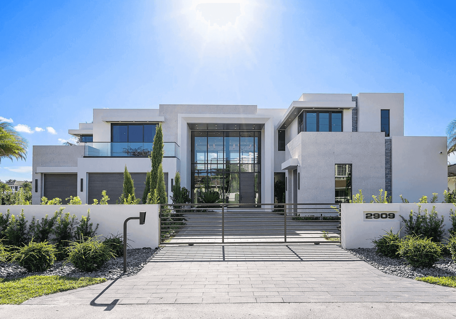 A large white house with a driveway and fence.