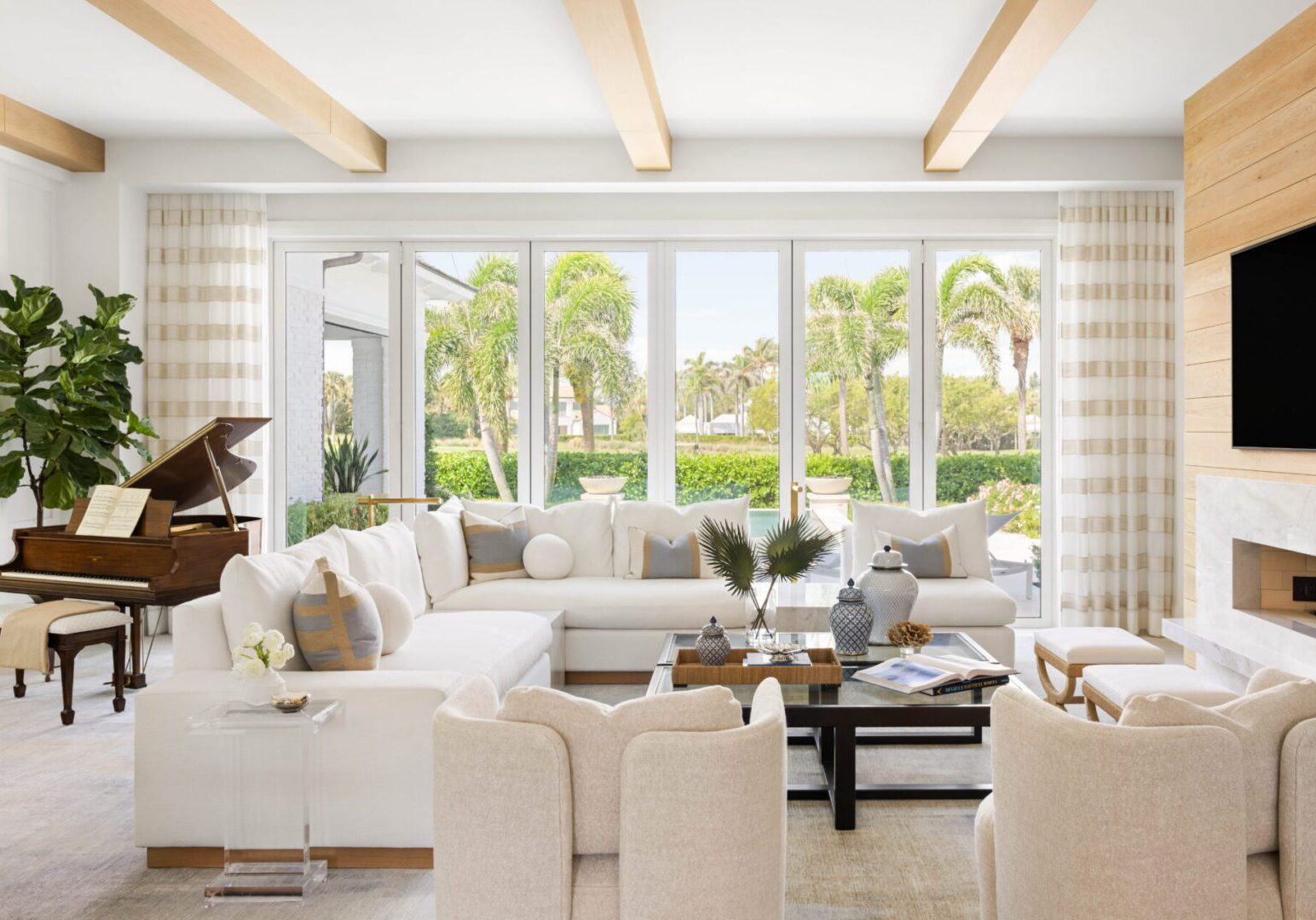 Living room with a sofa set with cushions, decors, houseplants, a piano, a television mounted on the wall